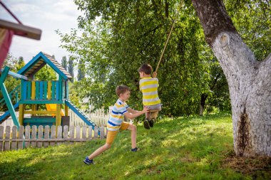 İki sevimli mutlu çocuk, şehir dışında dinlenirken bulduğu bir salıncakta eğleniyorlar. Çocuklarla aktif boş zaman.