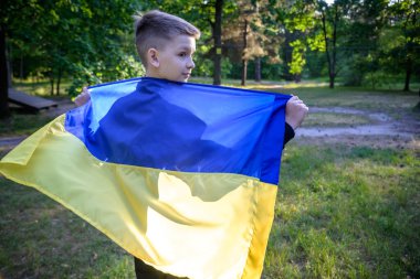 Ukrayna için dua et. Yaz parkını yöneten Ukrayna bayrağı taşıyan bir çocuk. Ulusal bayrak sallayan küçük çocuk barış için dua ediyor. Bağımsızlık Günü 'nü kutlayan mutlu çocuk.