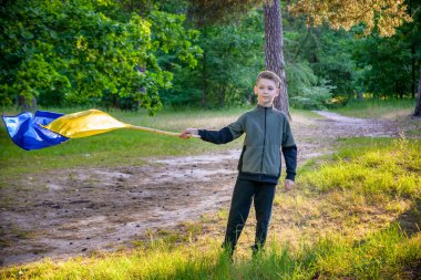 Ukraynalı çocuk elinde bayrak sallayarak Ukrayna 'daki savaşı gün batımında durdurmak için dua ediyor. Rusya 'nın Ukrayna' ya karşı savaşı. Savaşı Durdur.