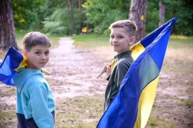 Ukrayna bayrakları iki çocuğun elinde. Çocuklar, rüzgarda dalgalanan sarı ve mavi Ukrayna bayrakları tutuyorlar. Ukrayna 'nın Bağımsızlık Günü. Bayrak Günü.