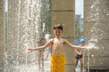 Çeşmede meditasyon yapan bir çocuk ZEN 'i bulur. Sıcak bir yaz gününde şehir çeşmesiyle oynayan bir çocuk. Fıskiyede eğlenen mutlu çocuklar. Yaz havası. Aktif eğlence, yaşam tarzı ve tatil.
