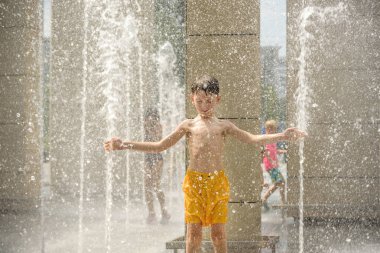 Çeşmede meditasyon yapan bir çocuk ZEN 'i bulur. Sıcak bir yaz gününde şehir çeşmesiyle oynayan bir çocuk. Fıskiyede eğlenen mutlu çocuklar. Yaz havası. Aktif eğlence, yaşam tarzı ve tatil.