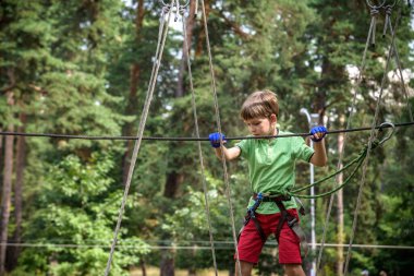 Halat parkında oynayan heyecanlı genç çocuk. Güneşli bir günde günlük giysiler ve spor ayakkabılar giyen beyaz bir çocuk. Çocuk konseptiyle aktif boş zaman.