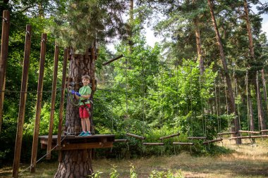 Halat parkında oynayan heyecanlı genç çocuk. Güneşli bir günde günlük giysiler ve spor ayakkabılar giyen beyaz bir çocuk. Çocuk konseptiyle aktif boş zaman.