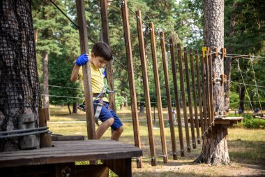 Halat parkında oynayan heyecanlı genç çocuk. Güneşli bir günde günlük giysiler ve spor ayakkabılar giyen beyaz bir çocuk. Çocuk konseptiyle aktif boş zaman.