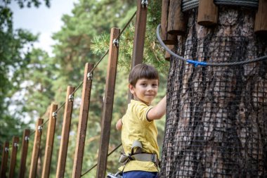 Halat parkında oynayan heyecanlı genç çocuk. Güneşli bir günde günlük giysiler ve spor ayakkabılar giyen beyaz bir çocuk. Çocuk konseptiyle aktif boş zaman.