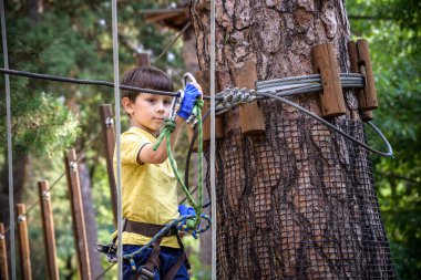Halat parkında oynayan heyecanlı genç çocuk. Güneşli bir günde günlük giysiler ve spor ayakkabılar giyen beyaz bir çocuk. Çocuk konseptiyle aktif boş zaman.