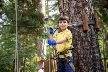 Halat parkında oynayan heyecanlı genç çocuk. Güneşli bir günde günlük giysiler ve spor ayakkabılar giyen beyaz bir çocuk. Çocuk konseptiyle aktif boş zaman.
