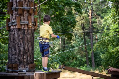 Halat parkında oynayan heyecanlı genç çocuk. Güneşli bir günde günlük giysiler ve spor ayakkabılar giyen beyaz bir çocuk. Çocuk konseptiyle aktif boş zaman.