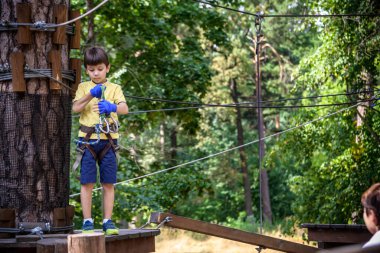Halat parkında oynayan heyecanlı genç çocuk. Güneşli bir günde günlük giysiler ve spor ayakkabılar giyen beyaz bir çocuk. Çocuk konseptiyle aktif boş zaman.