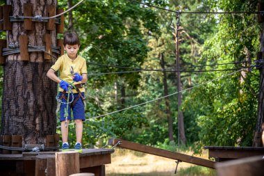 Halat parkında oynayan heyecanlı genç çocuk. Güneşli bir günde günlük giysiler ve spor ayakkabılar giyen beyaz bir çocuk. Çocuk konseptiyle aktif boş zaman.