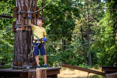 Halat parkında oynayan heyecanlı genç çocuk. Güneşli bir günde günlük giysiler ve spor ayakkabılar giyen beyaz bir çocuk. Çocuk konseptiyle aktif boş zaman.