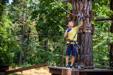 Halat parkında oynayan heyecanlı genç çocuk. Güneşli bir günde günlük giysiler ve spor ayakkabılar giyen beyaz bir çocuk. Çocuk konseptiyle aktif boş zaman.
