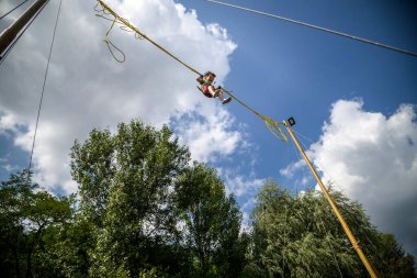 Çocuk bungee trambolinde zıplıyor. Sigortası ve esneyebilir lastikleri olan bir çocuk gökyüzüne asılı duruyor. Eğlence parkında mutlu çocukluk ve oyun kavramı.