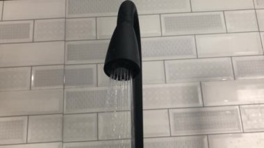 Mutfaktaki siyah su musluğu seramik duvarın arka planına su salıyor. Modern ve minimalist ev eşyaları. 4k video klipleri