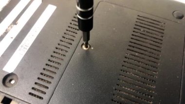 Profesyonel bir dizüstü bilgisayar teknisyeni tamir edilmek için bir dizüstü bilgisayardaki tornavidayı kullanarak vidayı söker. 4K video klibi