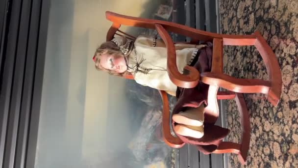 古いと非常に奇妙な人形は暖炉の背景にロッキングチェアに座っています それはホラー映画のように非常に怖いです 何かが起こるべきかのように07 2022カナダバンクーバー — ストック動画