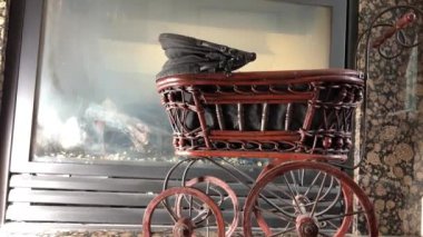 Şöminenin arka planında siyah bir bebek arabası var. Sanat eseri ince tekerlekler. El arabası, Brown tahtası ve kameranın önündeki yaşlı kırmızı kedi geçişi gibi.