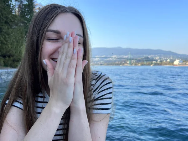 Kız Gülüyor Iki Eliyle Yüzünü Kapatıyor Okyanusun Arka Planına Karşı — Stok fotoğraf
