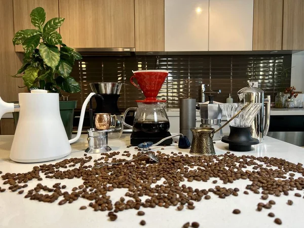 Different professional coffee equipment on the table next to the coffee flower as well as different accessories for brewing coffee Craft ad In foreground beans are scattered on the table
