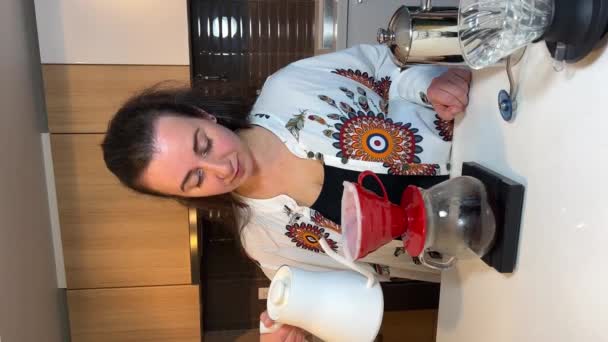 黒髪の美しい若い女性が水を注ぐコーヒーの花の横にテーブルの上に異なるプロのコーヒー機器だけでなく コーヒーを醸造するためのさまざまなアクセサリークラフト広告垂直ビデオ — ストック動画