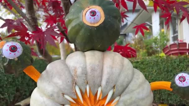 野菜や果物の彫刻芸術秋の収穫祭のためのカボチャのハロウィーンの装飾に異なる文字や顔を彫り歯と牙を持つ三つ目のモンスター — ストック動画