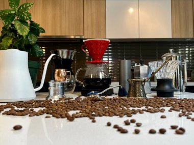 Various devices for craft coffee beans lie on the table On the white countertop in the kitchen the camera slowly floats, removing all the details in pouring coffee dripping after brewing clipart
