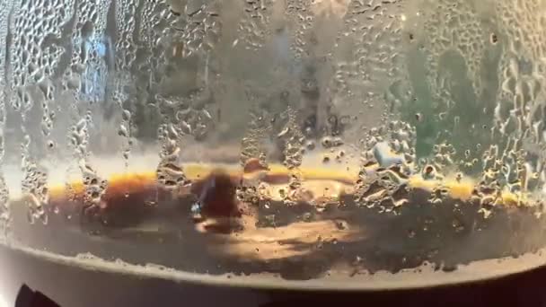 水の滴がコーヒー泡の極端なクローズアップを排水して 間違っガラスのために閉じます マクロな質感と背景ガラスカップの中のコーヒー豆とコーヒー豆 — ストック動画
