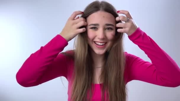 아름다운 소녀가 손가락으로 머리를 세우고 미소를 프레임을 들여다보고 있습니다 그녀는 — 비디오