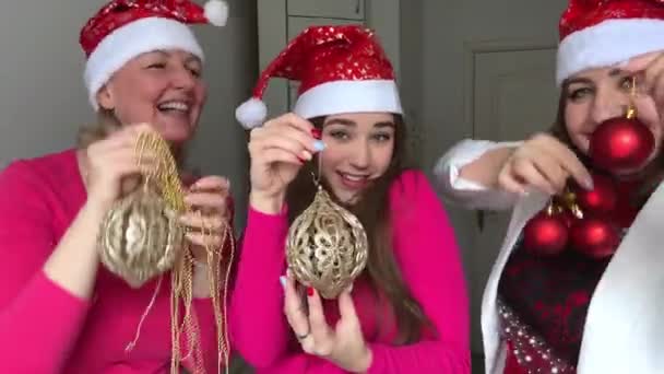 笑顔の多くの笑いの喜び3人の女性は新年を祝っている 彼らは彼らの手の中に雪の結晶と赤い帽子を身に着けていますクリスマスツリーおもちゃパーティー通信愛の友情の女性が踊る — ストック動画