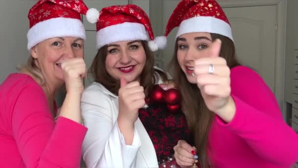 三个女人在庆祝新年 她们头戴红帽子 头戴雪花 参加聚会 进行交流 爱情友谊在框子里显示了自己的大拇指 — 图库视频影像