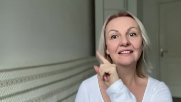 Ενηλίκων Ξανθιά Γυναίκα Διαφημίζει Κάτι Λευκό Φόντο Δείχνει Προς Την — Αρχείο Βίντεο