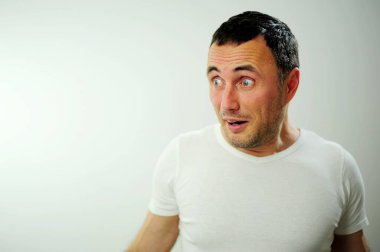 Çekici, tıraşsız adam şaşkınlıkla şaşkına döndü. Şaşırdı yüz ifadesi ve şok duygusu. Mavi gözler, gri saçlar.