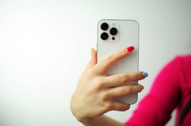iPhone Apple 13 Mini kadın ellerinde, akıllı telefon beyaz elde çok renkli manikürlü izole edilmiş.