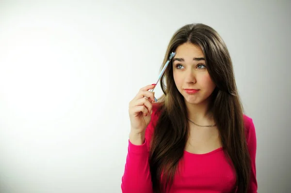 stock image young woman girl playing pen in hand online learning reluctance to learn student life write dictation drawing pencil girl in a pink sweater on a white studio scratch your hair with a pen and think