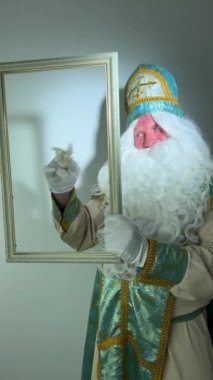 Aziz Nicholas güzel beyaz bir kalemle boş bir çerçeve çizer. Muhteşem bir harf. Sihirli bir hareketi vardır. Beyaz tüylü bir sakalı vardır.