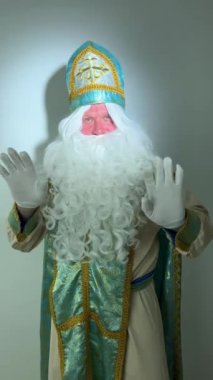 Noel Baba turkuaz takım elbisesinin kurucusu Aziz Nicholas 'ın farklı pozitif duyguları vardı. Geleneksel bir dini şapkayla, tıpkı bir papazın cübbesi ve kemeri olması gibi.
