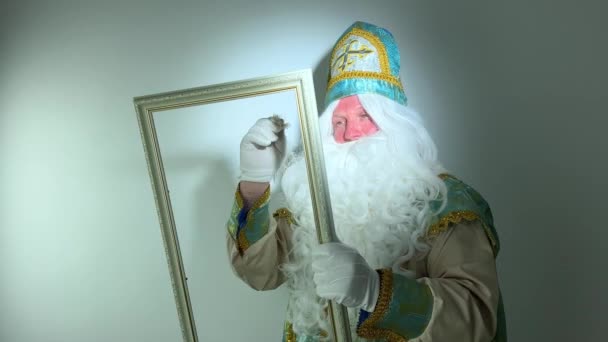 聖ニコラスは美しい白いペンで空のフレームに描かれています素晴らしい手紙魔法のアクション彼は白いふわふわひげ彼はサンタクラスクリスマスの前に来る金と青のスーツを持っています — ストック動画