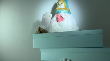 Noel Baba Dondurucu Moroz Ivanovich kış ayı Ocak ayının Ocak ayında Büyükbaba Moroz elini sallayarak kutuları tutuyor ve onları parmağıyla işaret ediyor.