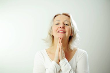 Bir kadın ellerini çırpar, sevinir, başını kaldırır, mutlu ve mutlu görünür. Tanrıya şükür bir şey oldu. Çok mutlu. Minnettarlık yüzünü sıkar, gözlerini kapatır.