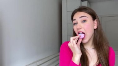 Pastel pembe arka planda yuvarlak pembe şekerlemeler. Bir pasta şefinin ellerinde ev yapımı renkli şekerlemeler. İştah açıcı tatlı genç kız lokum yiyor.