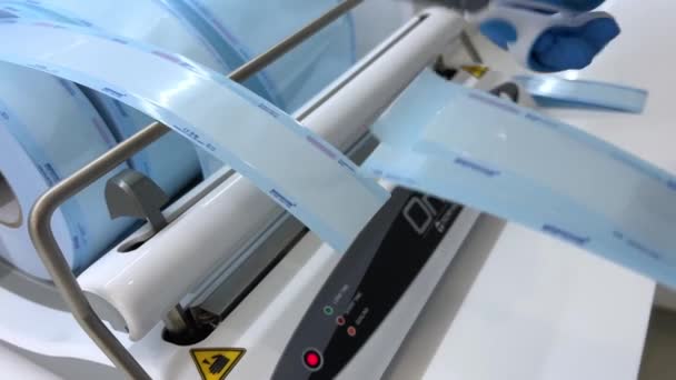 의사들은 기계를 사용하여 비닐봉지에자 가결합하기 기구를 포장하는 장갑에 보조한다 정확성 — 비디오