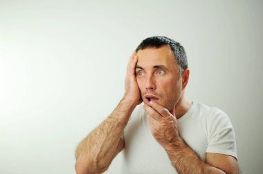 Duygusal portresi olan adam soluk soluğa kalıyor. Duygusal stres hakkında. Gri beyaz stüdyo arka planında izole edilmiş duygular.