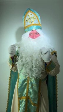 Noel 'de Aziz Niklas dans eder ve kollarını sallar. Sizi dans etmeye davet eder. Güzel kilise kıyafeti.