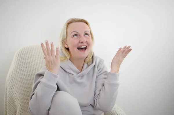 Kanepede oturan, arkadaşlarıyla görüntülü konuşma yapan, kafasından yakın plan fotoğraf çeken olgun sarışın kadın. Web kamerası görüntüsü gülüyor orta yaşlı kadın eğleniyor, yetişkin çocuklarla internette konuşuyor.