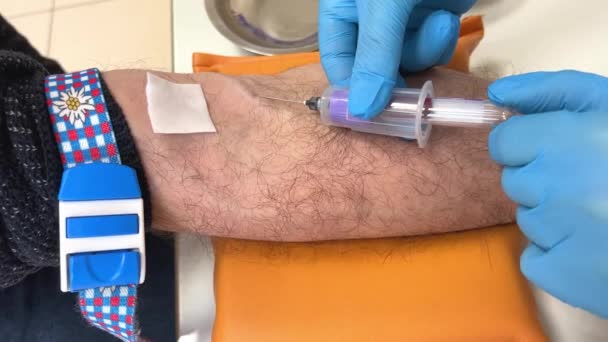 看護師は 献血ポイントまたは手袋で針で静脈を貫通分析研究所で血液を取って病院で点滴注入のための静脈に針を挿入静脈から血を引く — ストック動画