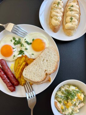 Sağlıklı kahvaltı için avokado yumurtalı sandviç ve kahve. Avokado püresiyle tam tahıllı tost, kızarmış yumurta ve beyaz masada organik mikro sebzeler.