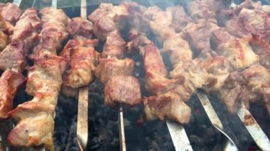 Process of cooking delicious shish kebab on metal skewer in summer outdoors. Grilling shashlik on barbecue grill. Marinated kebab is grilled on charcoal. Skewers on skewers. Weekend picnic Street food