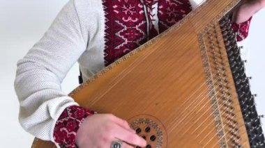 Elinde kobza müzik aleti olan yakışıklı genç adam tekerlekli sandalyede beyaz arka planda oturuyor bacaksız savaş gazisi Ukraynalı nakışlı gömlek Vyshyvanka 'nın ulusal sembolleri