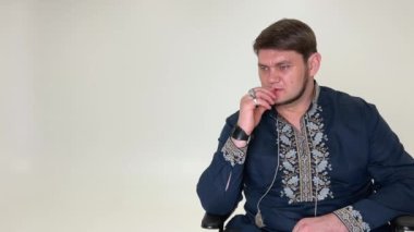 Duman üfleyerek Ukarinsky Kazak piposu tüttürüyor. Ciddi ve düşünceli bir şekilde mavi bir vyshyvanka giyinmiş, beyaz işlemeli, düz sakallı, mavi gözlü Ukraynalı asker kahramanı.